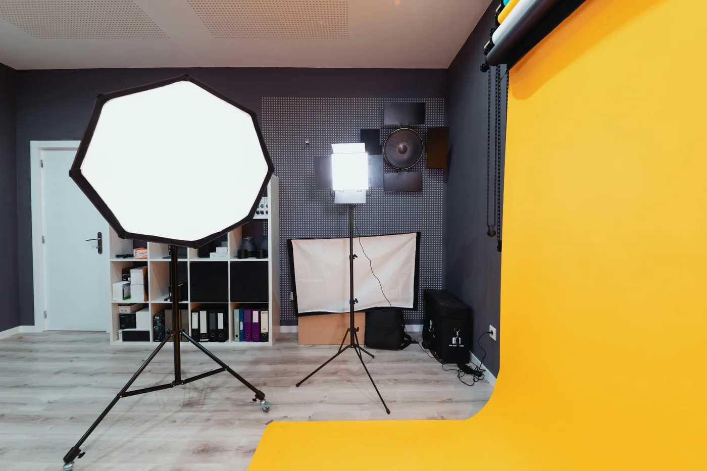 Un studio photographique professionnel avec softbox, fond jaune et équipement de lumière, évoquant le geste de captation et de création