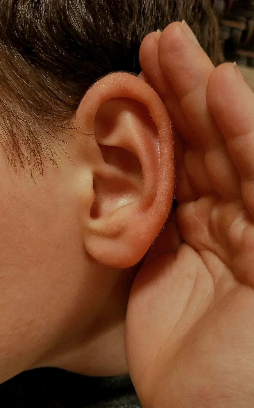 Une main en coupe derrière l’oreille, geste d’écoute attentive